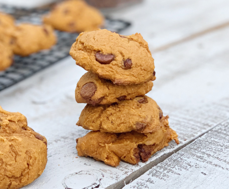 Stack of four pumpkin chocolate chip cookies on wooden table